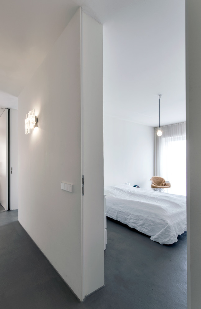 Mittelgroßes Modernes Hauptschlafzimmer mit weißer Wandfarbe und Betonboden in Mailand