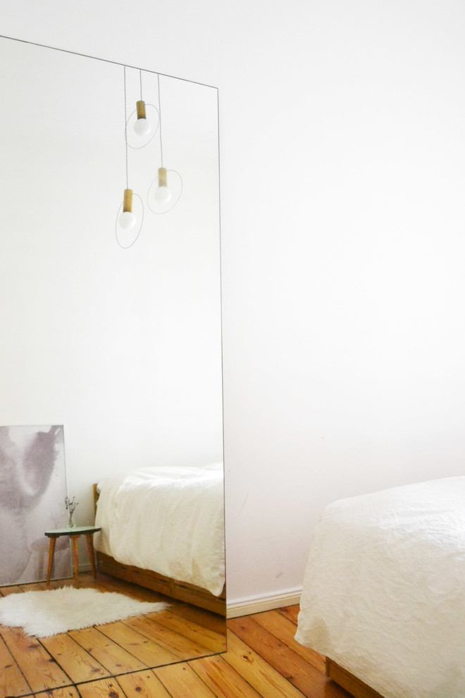 Imagen de dormitorio principal actual pequeño con paredes blancas, suelo de madera en tonos medios y suelo marrón