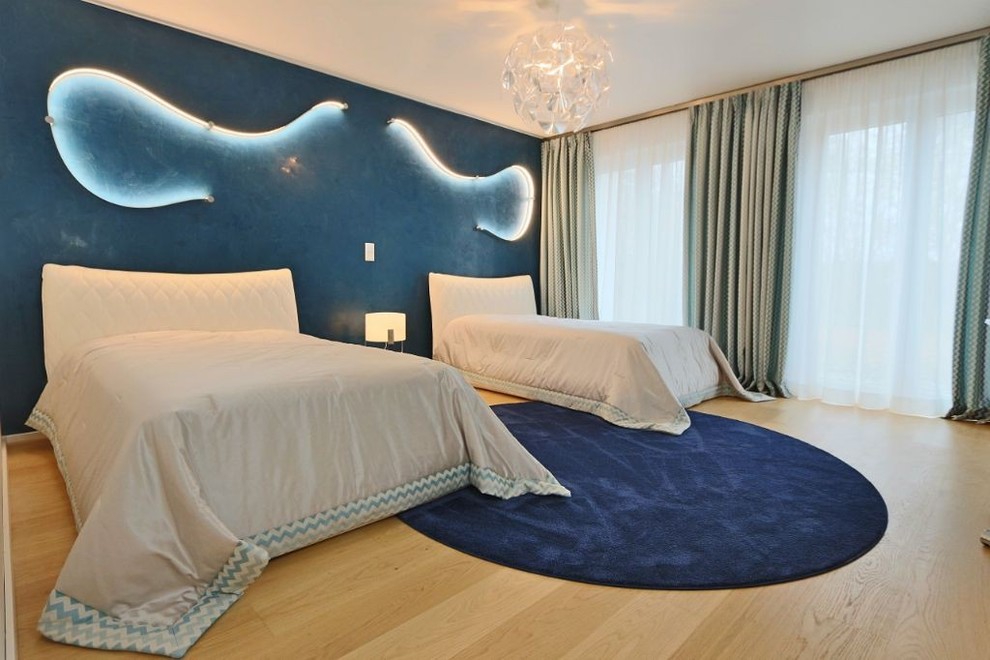 Großes Modernes Hauptschlafzimmer ohne Kamin mit blauer Wandfarbe und hellem Holzboden in München
