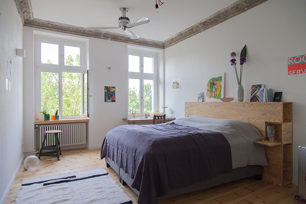 Foto de dormitorio principal ecléctico de tamaño medio con paredes blancas, suelo de madera clara y suelo marrón