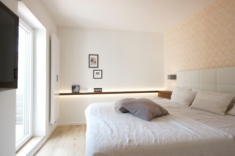Inredning av ett modernt mellanstort sovrum, med beige väggar och ljust trägolv