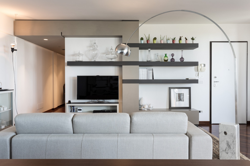 Cette image montre un grand salon gris et blanc design avec un mur blanc, un sol en bois brun, un téléviseur indépendant et un sol marron.