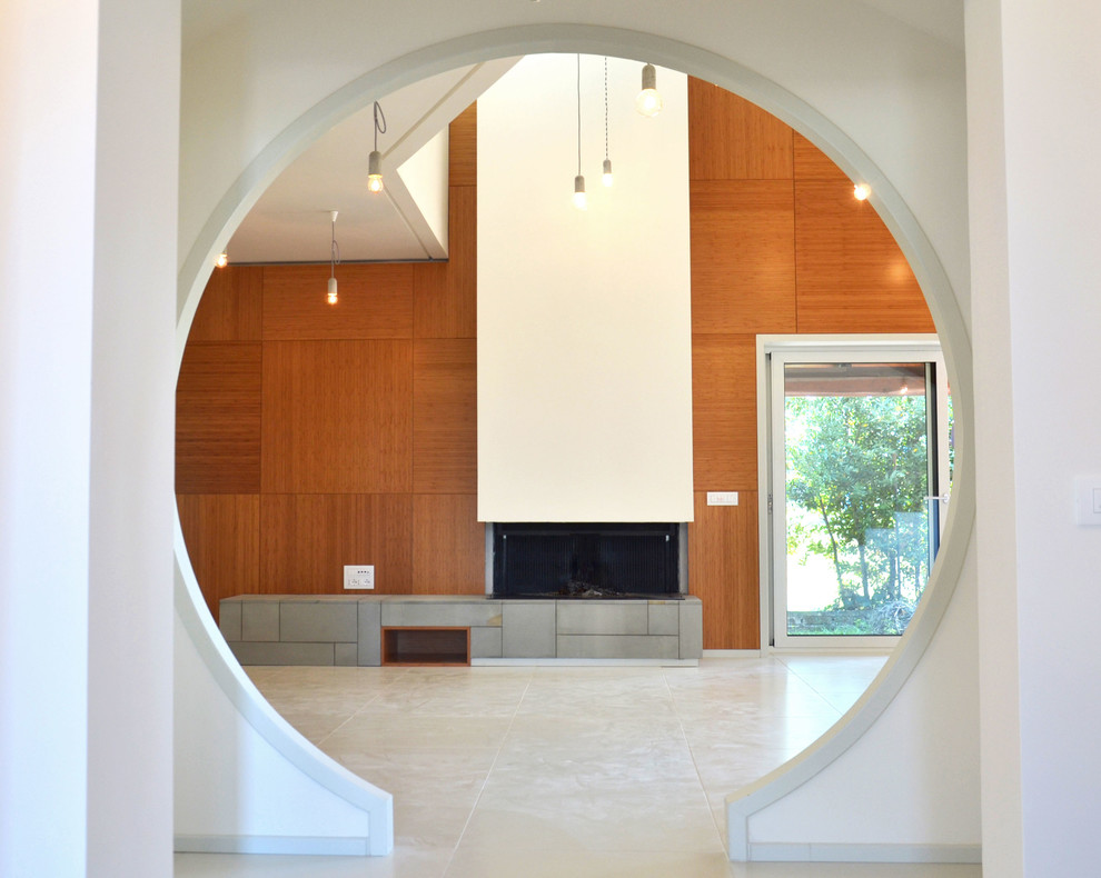 Imagen de salón abierto minimalista grande con paredes marrones, chimenea lineal, marco de chimenea de yeso, suelo de cemento, televisor colgado en la pared y suelo blanco