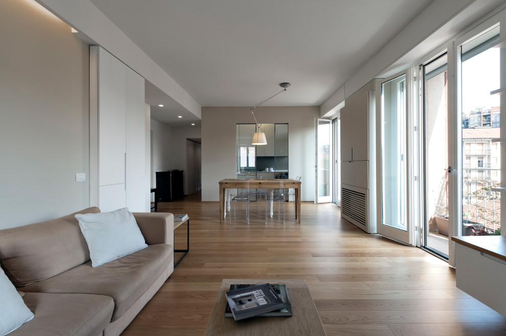Diseño de salón abierto moderno grande con paredes grises y suelo de madera clara