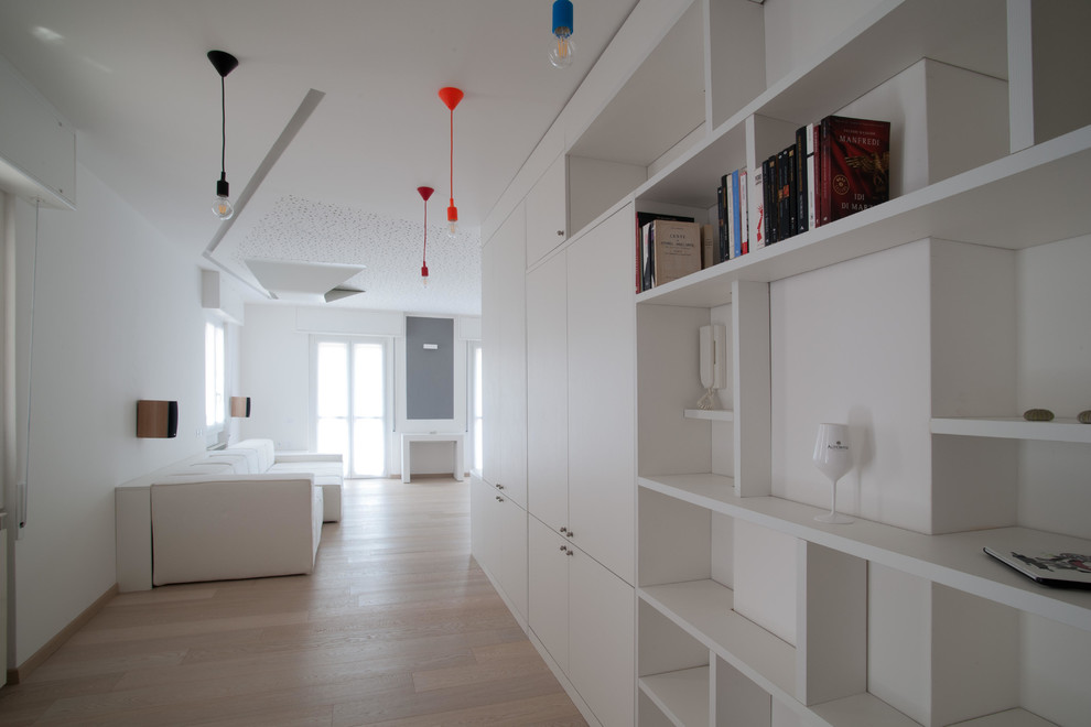 Идея дизайна: большая открытая гостиная комната в современном стиле с с книжными шкафами и полками, белыми стенами, светлым паркетным полом, телевизором на стене и коричневым полом без камина