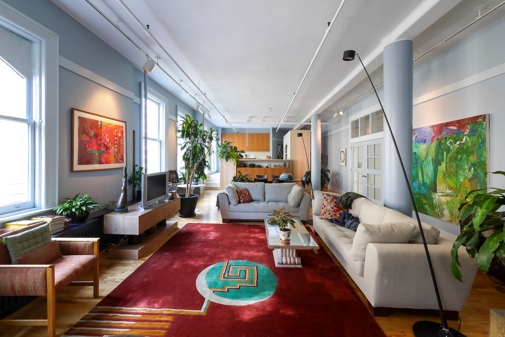 Ispirazione per un ampio soggiorno bohémian aperto con pareti blu, pavimento in legno massello medio, TV autoportante e pavimento giallo