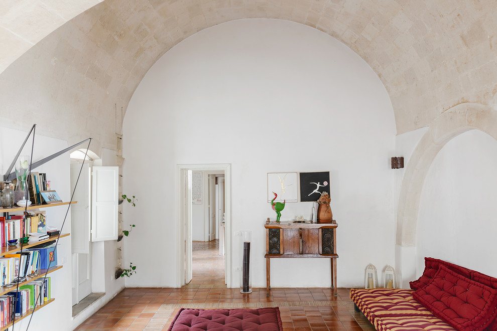 На фото: гостиная комната в средиземноморском стиле с полом из терракотовой плитки