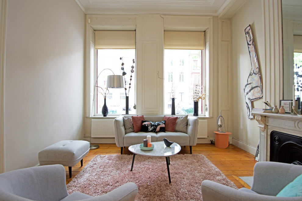 Cette image montre une salle de séjour design avec un mur beige, parquet clair, une cheminée standard et un manteau de cheminée en pierre.
