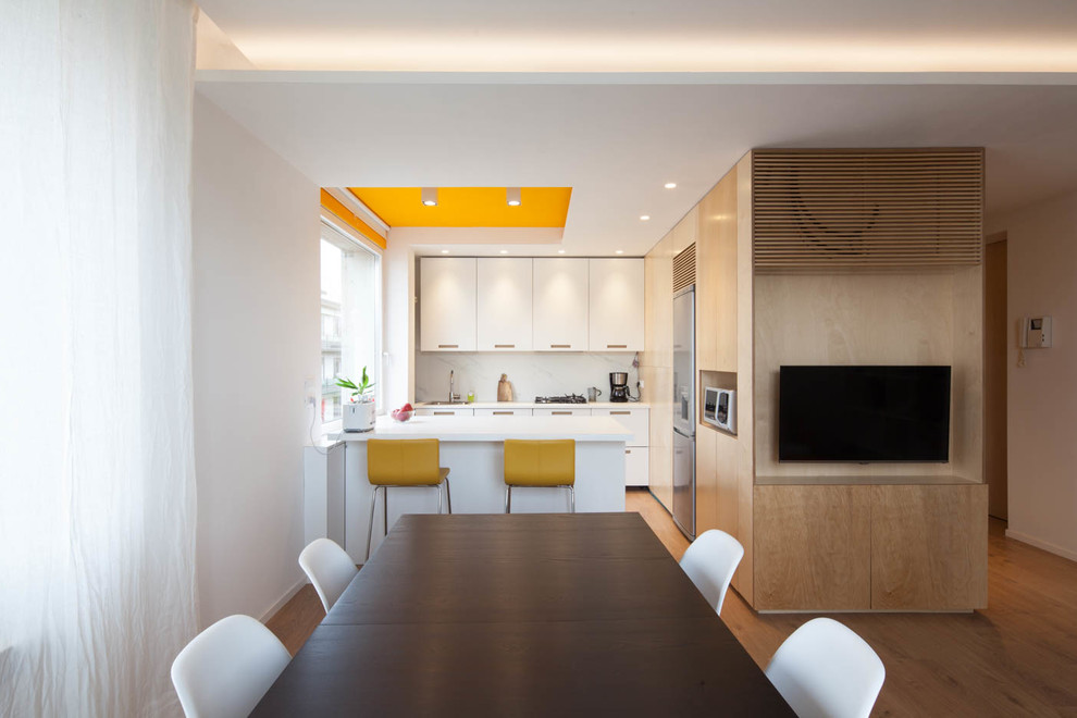 Diseño de salón abierto actual de tamaño medio con paredes blancas, suelo de madera en tonos medios y televisor colgado en la pared
