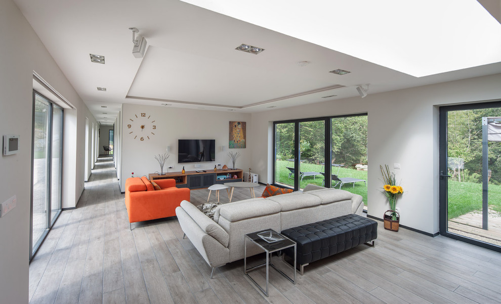 Immagine di un soggiorno contemporaneo aperto con pareti grigie, pavimento in legno massello medio, nessun camino, TV a parete e pavimento grigio