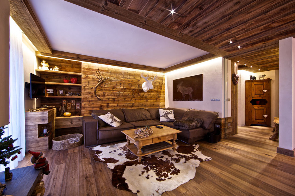 Foto di un soggiorno stile rurale aperto con pareti bianche, pavimento in legno massello medio e TV a parete