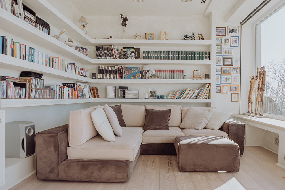 Inspiration för moderna vardagsrum, med ljust trägolv, ett bibliotek, vita väggar och beiget golv
