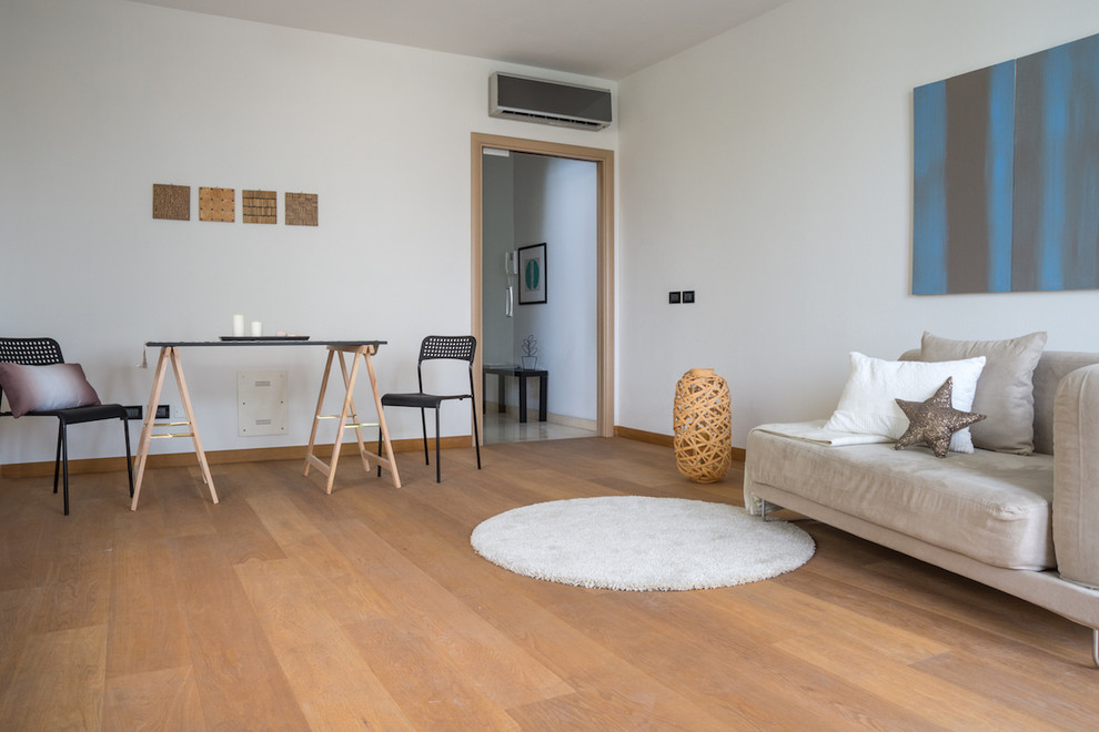 Danish medium tone wood floor living room photo in Bologna with white walls and no fireplace