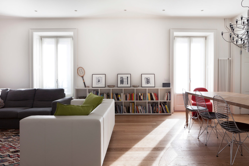 Immagine di un grande soggiorno contemporaneo aperto con libreria, pareti bianche, parquet chiaro, nessun camino e TV a parete