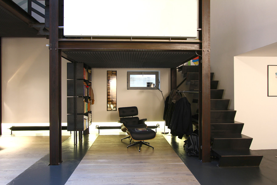 Imagen de sala de estar con biblioteca industrial extra grande con paredes blancas, suelo de cemento, pared multimedia y suelo gris
