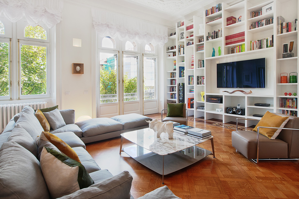 Photo of a contemporary enclosed living room in Milan with a reading nook, white walls, medium hardwood flooring and a built-in media unit.