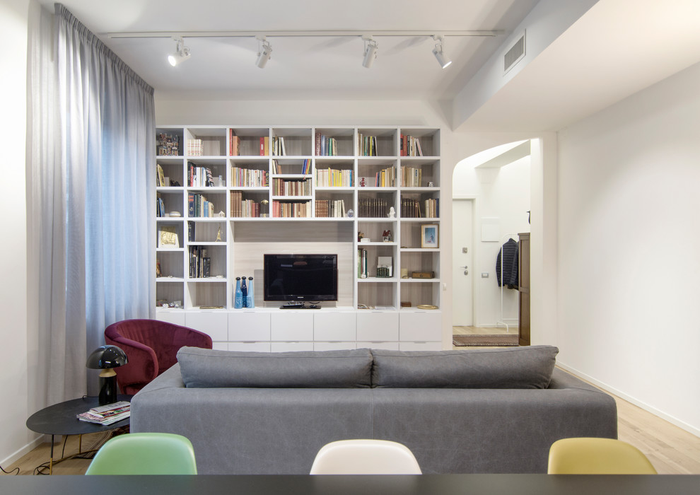 Immagine di un soggiorno minimal aperto e di medie dimensioni con libreria, pareti bianche, parquet chiaro e parete attrezzata