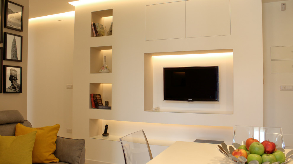 Ejemplo de biblioteca en casa abierta actual pequeña con paredes beige, suelo de baldosas de porcelana y televisor colgado en la pared