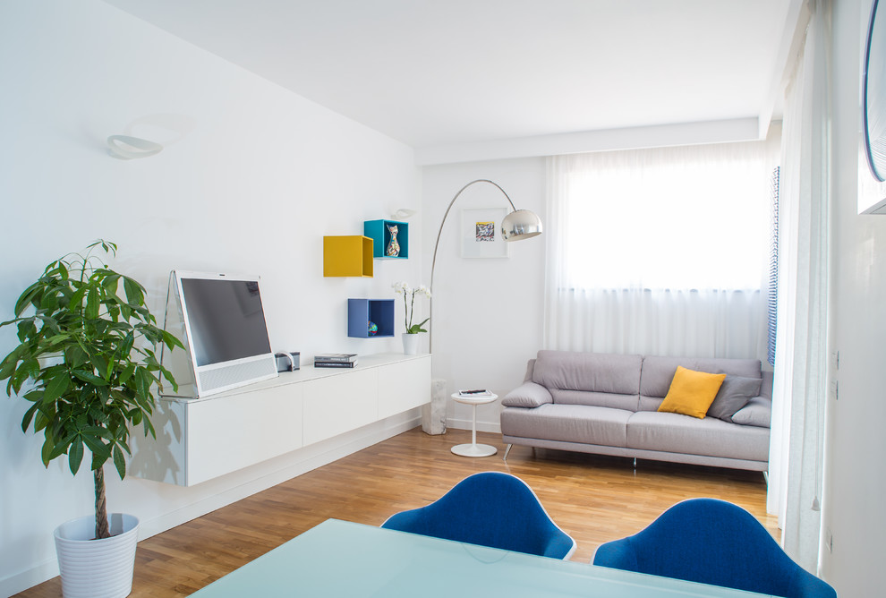 Modernes Wohnzimmer mit weißer Wandfarbe, braunem Holzboden und freistehendem TV in Neapel
