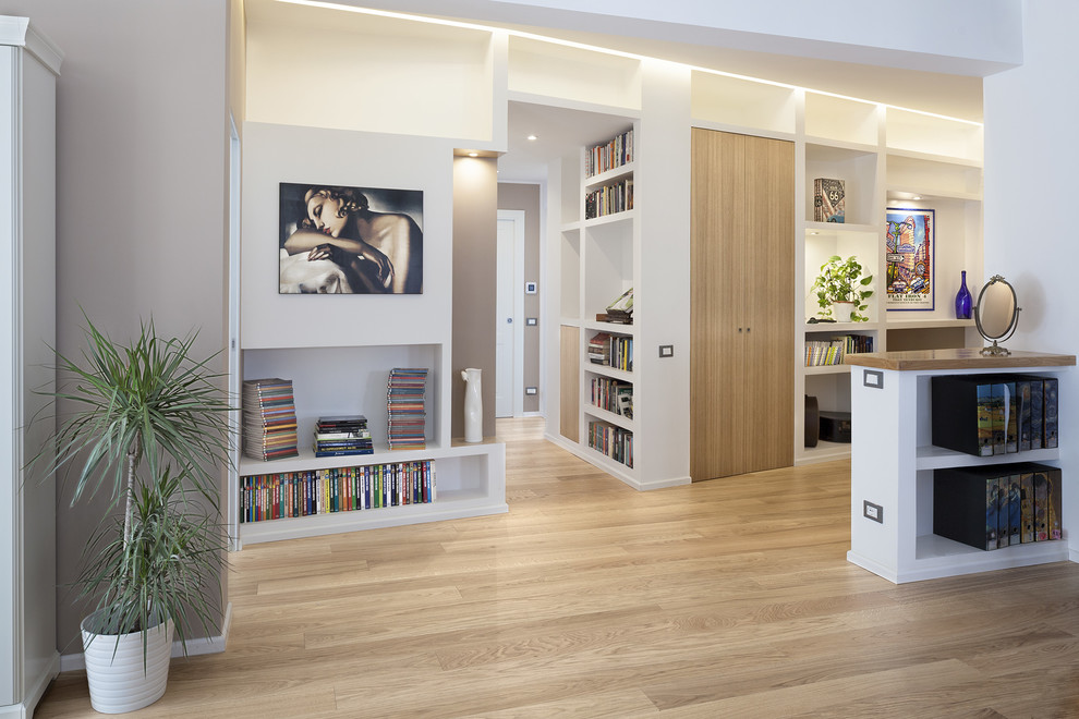 Foto di un soggiorno minimalista aperto con libreria, pareti beige e parquet chiaro