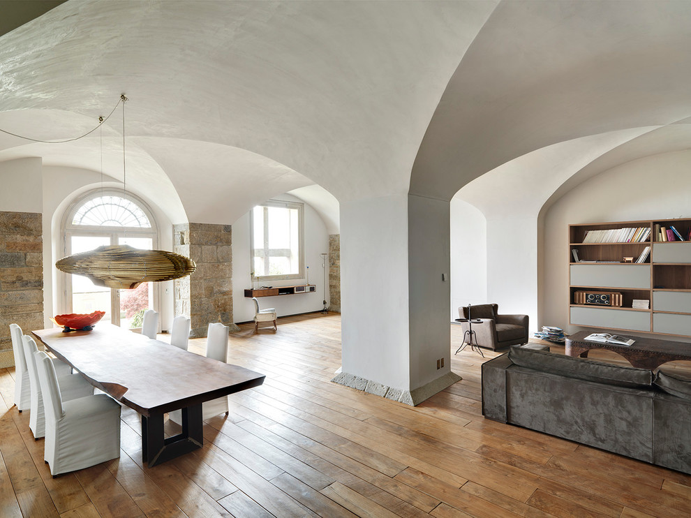 Inspiration pour un grand salon design ouvert avec un mur blanc, un sol en bois brun et un téléviseur dissimulé.