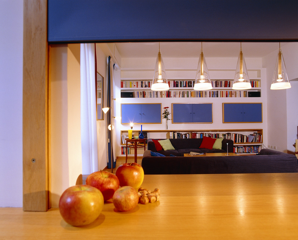 Esempio di un piccolo soggiorno moderno aperto con TV nascosta, pavimento marrone, libreria, pareti marroni, parquet chiaro e nessun camino