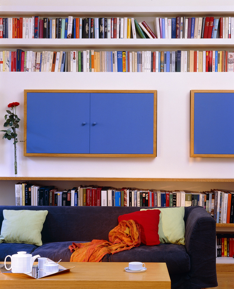 Immagine di un piccolo soggiorno minimalista aperto con pavimento in legno massello medio, TV nascosta, pavimento marrone, libreria, pareti bianche e nessun camino
