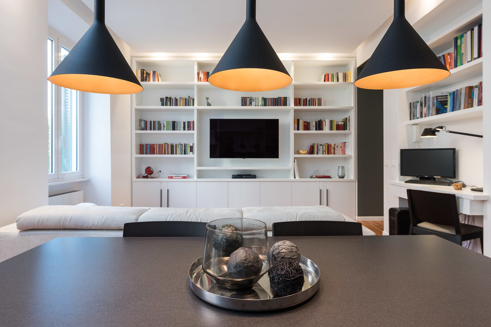Ispirazione per un soggiorno design aperto con libreria, pareti bianche, parquet chiaro e TV a parete