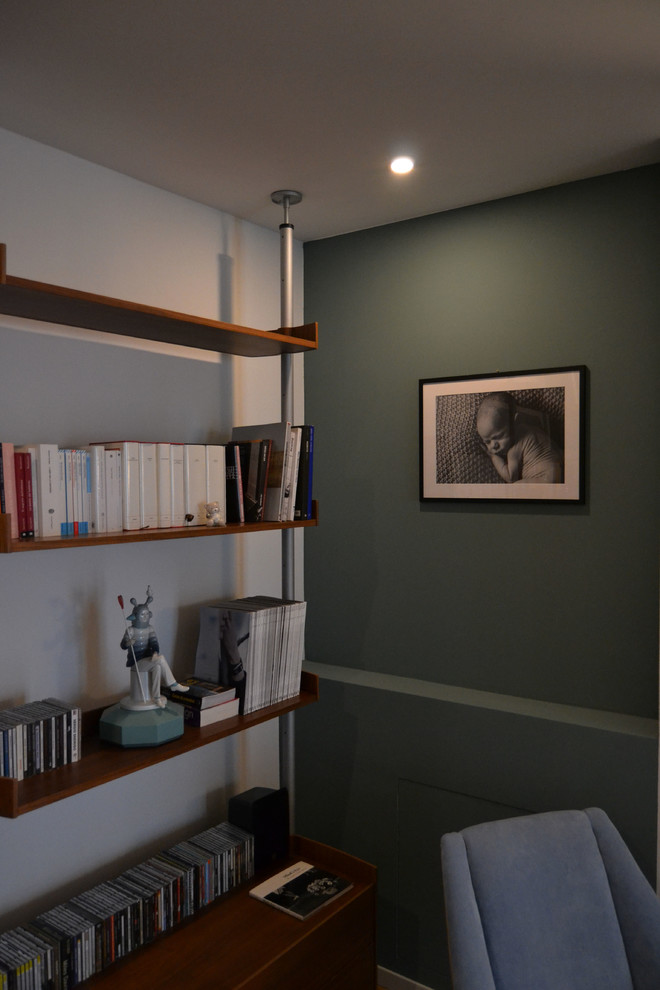 Foto de sala de estar con biblioteca abierta moderna pequeña con paredes azules, suelo de madera clara y televisor colgado en la pared