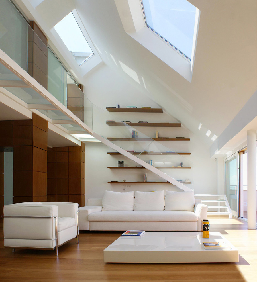 Cette image montre un salon design avec un mur blanc, un sol en bois brun, une salle de réception et un escalier.