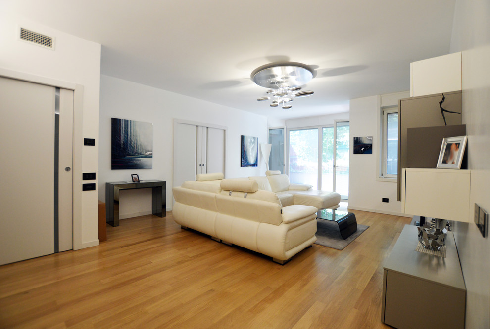 Immagine di un piccolo soggiorno minimal aperto con libreria, pareti bianche, parquet chiaro, TV a parete e pavimento marrone