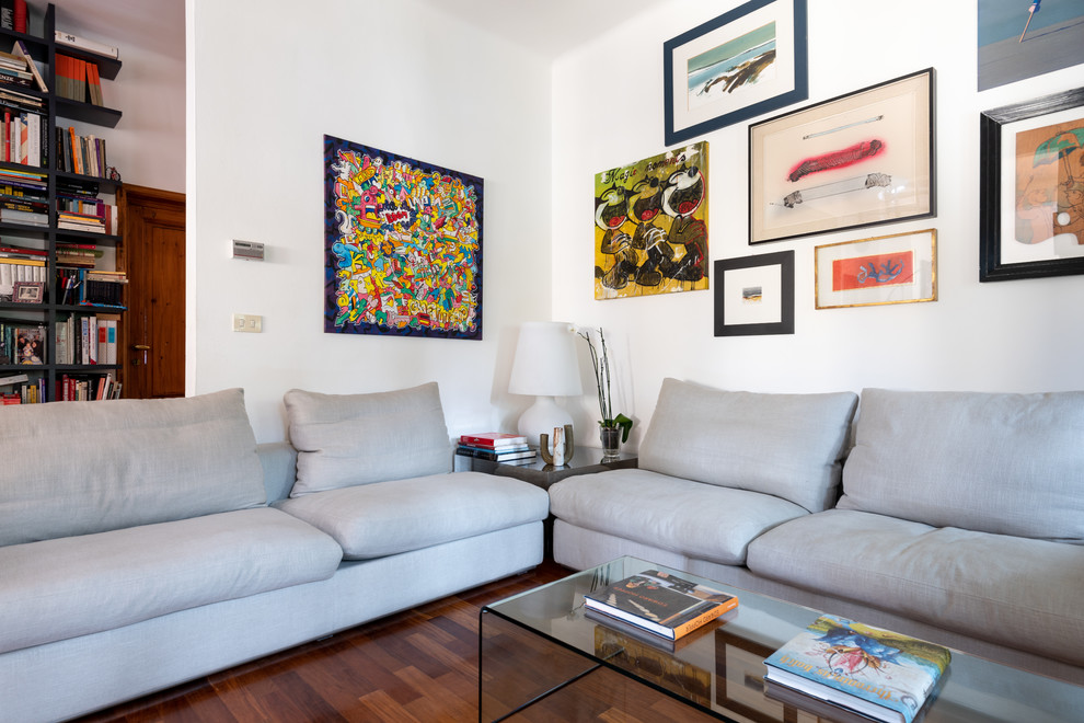 Diseño de sala de estar abierta moderna de tamaño medio con paredes blancas, suelo de madera oscura, televisor independiente y suelo marrón