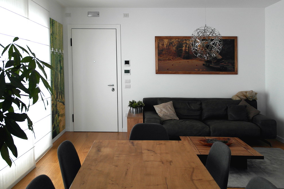 Ejemplo de salón tipo loft actual pequeño con paredes blancas, suelo de madera clara, televisor colgado en la pared y suelo marrón
