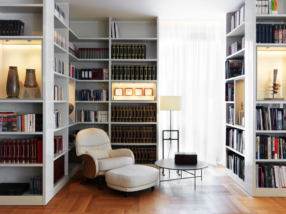 Réalisation d'une petite salle de séjour design avec une bibliothèque ou un coin lecture, un mur blanc, un sol en bois brun et un sol marron.