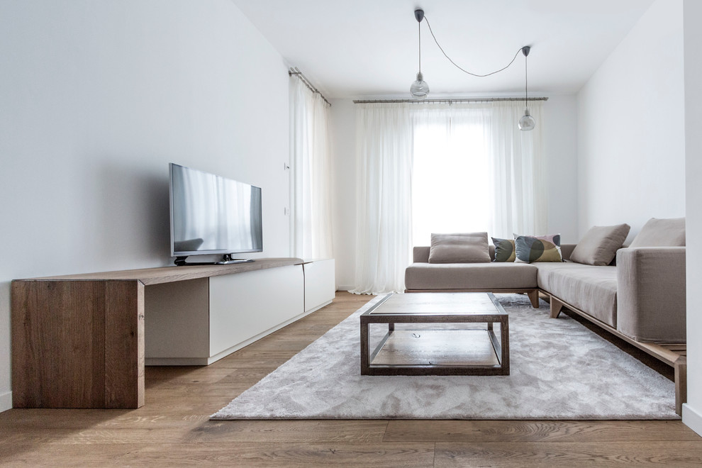 Immagine di un grande soggiorno minimalista con pareti bianche, pavimento in legno massello medio e TV autoportante