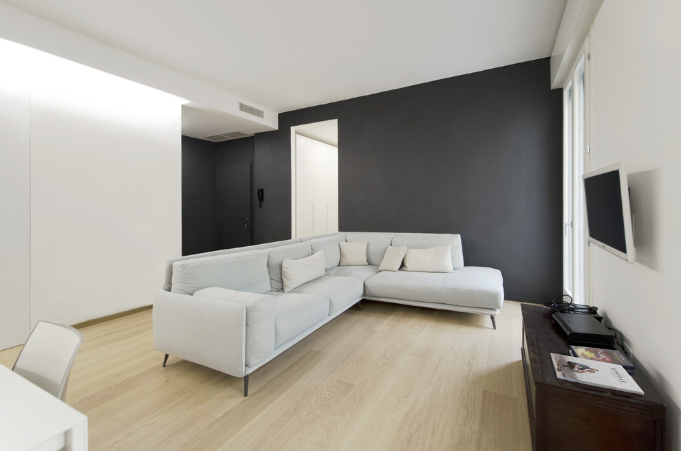 This is an example of a small contemporary open plan living room in Other with multi-coloured walls, light hardwood flooring, a wall mounted tv and brown floors.