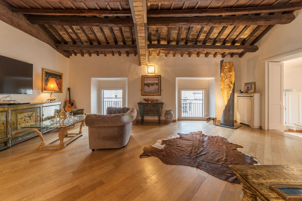 Immagine di un soggiorno mediterraneo con pareti beige, pavimento in legno massello medio, TV a parete e pavimento marrone
