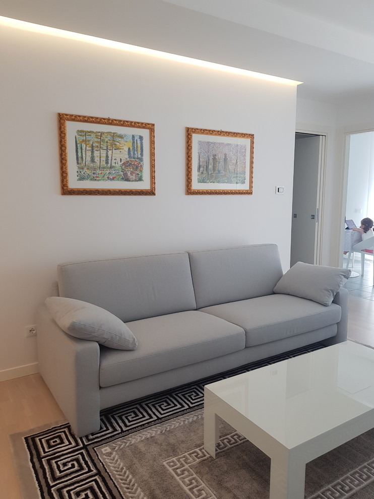 Foto di un grande soggiorno minimalista aperto con pareti bianche, parquet chiaro, TV a parete e pavimento beige