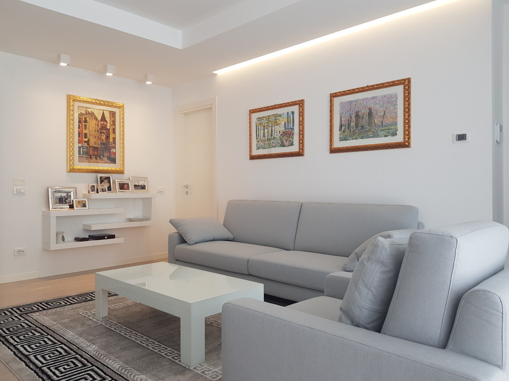 Imagen de sala de estar abierta minimalista grande con paredes blancas, suelo de madera clara, televisor colgado en la pared y suelo beige