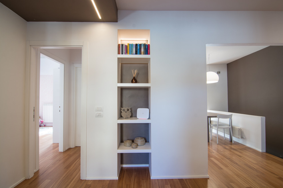 Modelo de biblioteca en casa abierta contemporánea pequeña con paredes marrones, suelo de madera clara y pared multimedia