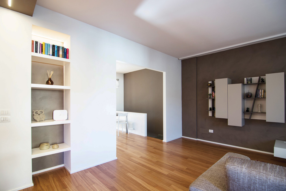 Foto di un piccolo soggiorno minimal aperto con libreria, pareti marroni, parquet chiaro e parete attrezzata