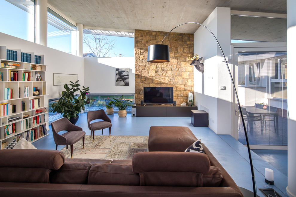Cette image montre un salon design ouvert avec une bibliothèque ou un coin lecture, un mur blanc, un téléviseur indépendant et un sol bleu.