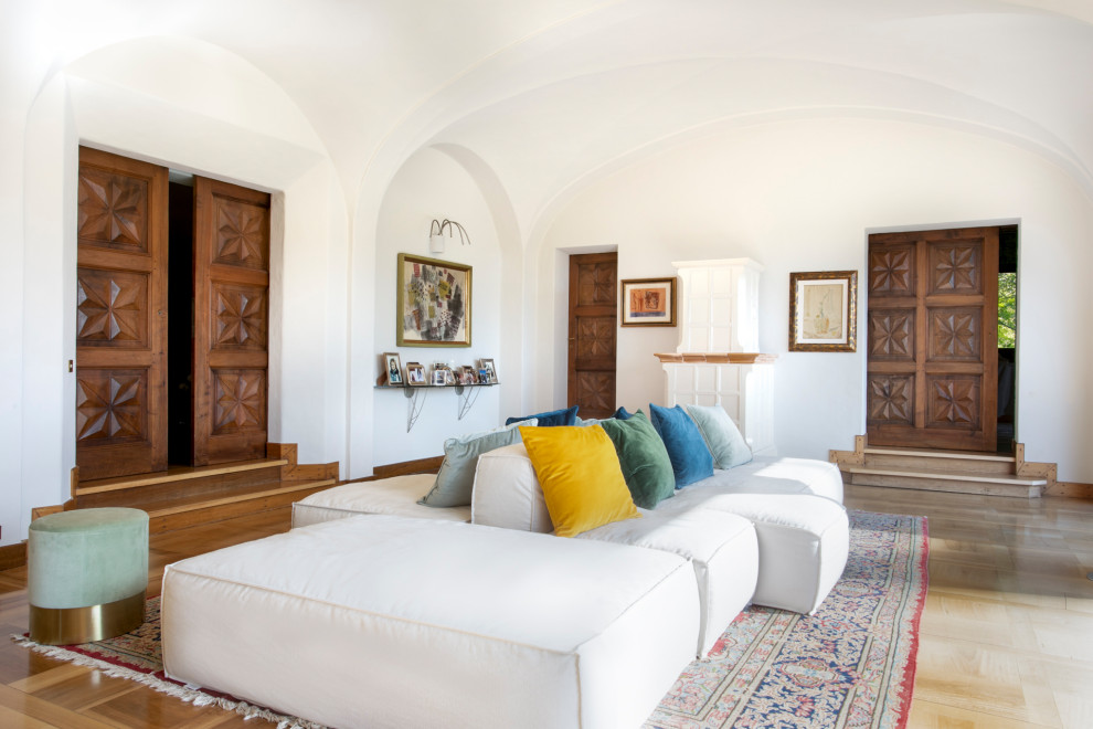 Aménagement d'un très grand salon méditerranéen ouvert avec parquet clair, un manteau de cheminée en bois, aucun téléviseur, un sol beige, un plafond voûté et un mur blanc.