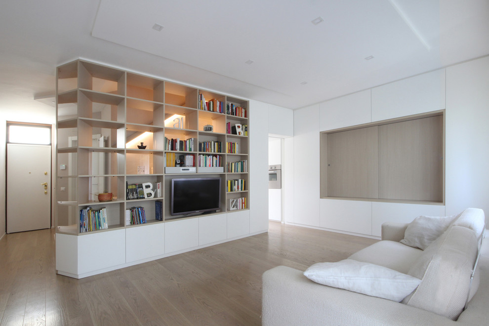Foto de biblioteca en casa abierta minimalista de tamaño medio con paredes blancas, suelo de madera clara, pared multimedia y suelo marrón