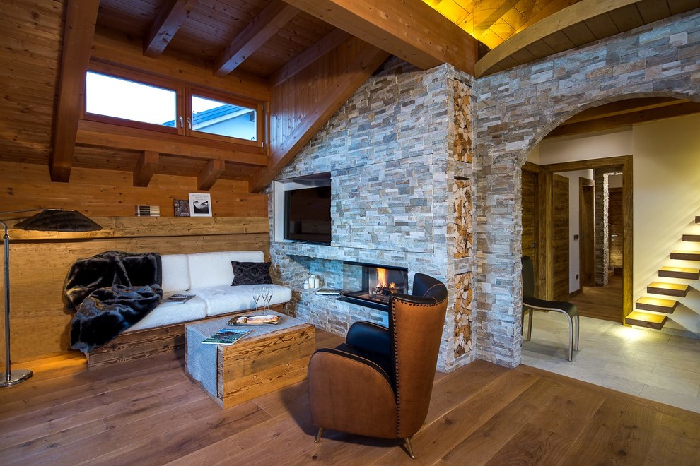Diseño de sala de estar abierta rural de tamaño medio con chimenea lineal, marco de chimenea de piedra y televisor independiente