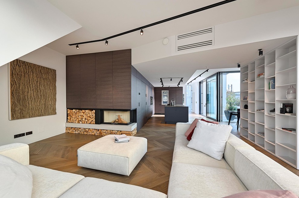 Пример оригинального дизайна: открытая гостиная комната среднего размера в современном стиле с белыми стенами, паркетным полом среднего тона, угловым камином и фасадом камина из дерева