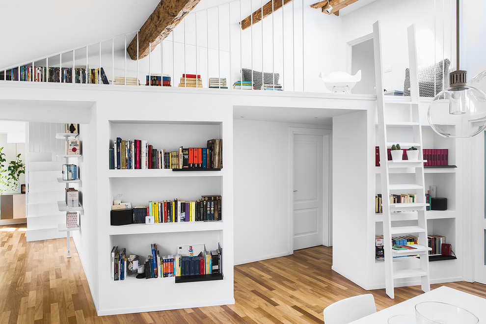 Foto på ett mellanstort funkis allrum med öppen planlösning, med ett bibliotek, ljust trägolv och brunt golv