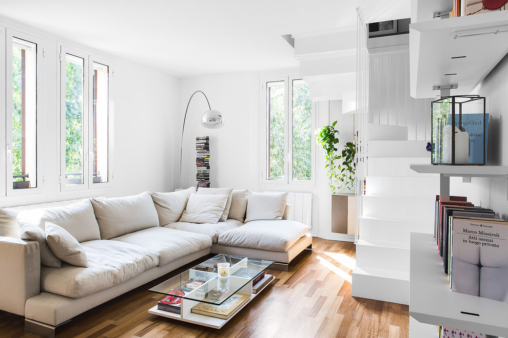 Ejemplo de sala de estar con biblioteca abierta contemporánea de tamaño medio sin chimenea con paredes blancas y suelo de madera en tonos medios
