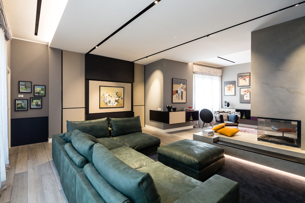 Пример оригинального дизайна: огромная открытая гостиная комната в стиле фьюжн с черными стенами, темным паркетным полом, двусторонним камином, фасадом камина из бетона, телевизором на стене и серым полом