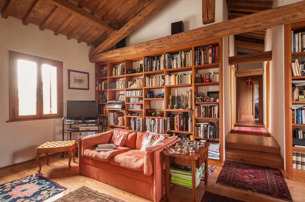 Imagen de biblioteca en casa campestre con paredes blancas, suelo de madera clara y televisor independiente